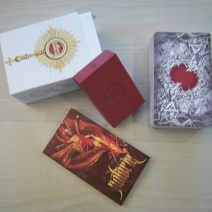 May include: A red box with a white circle and the word "WITCH" inside. A white box with a gold design and a cross. A deck of cards with a black and white design and a red circle in the center. The cards have the word "Witchcraft" printed on the side.