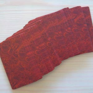 May include: A deck of playing cards with a red, patterned back. The cards are stacked and fanned out, showing the intricate design.