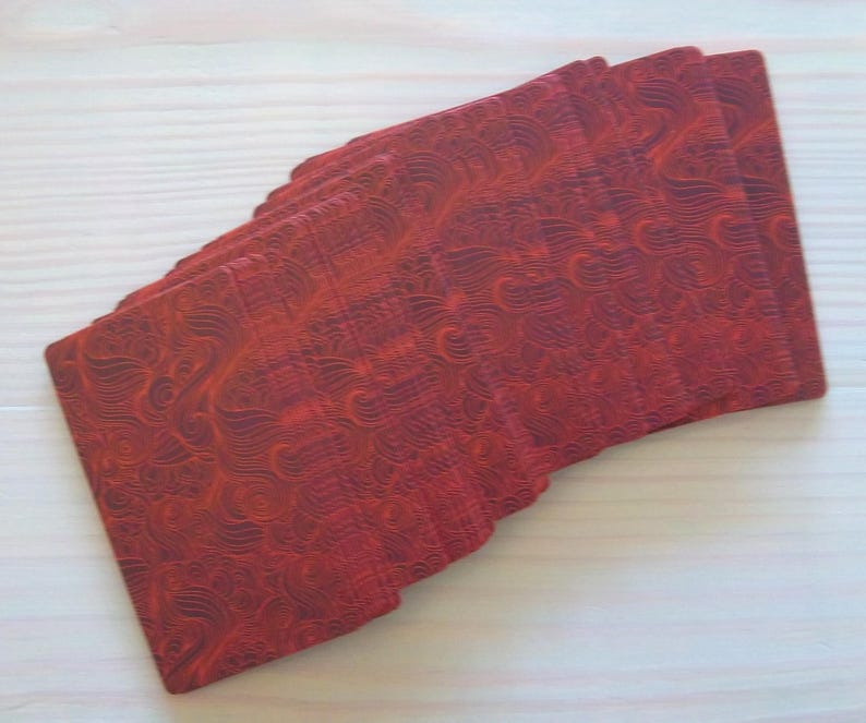 May include: A deck of playing cards with a red, patterned back. The cards are stacked and fanned out, showing the intricate design.