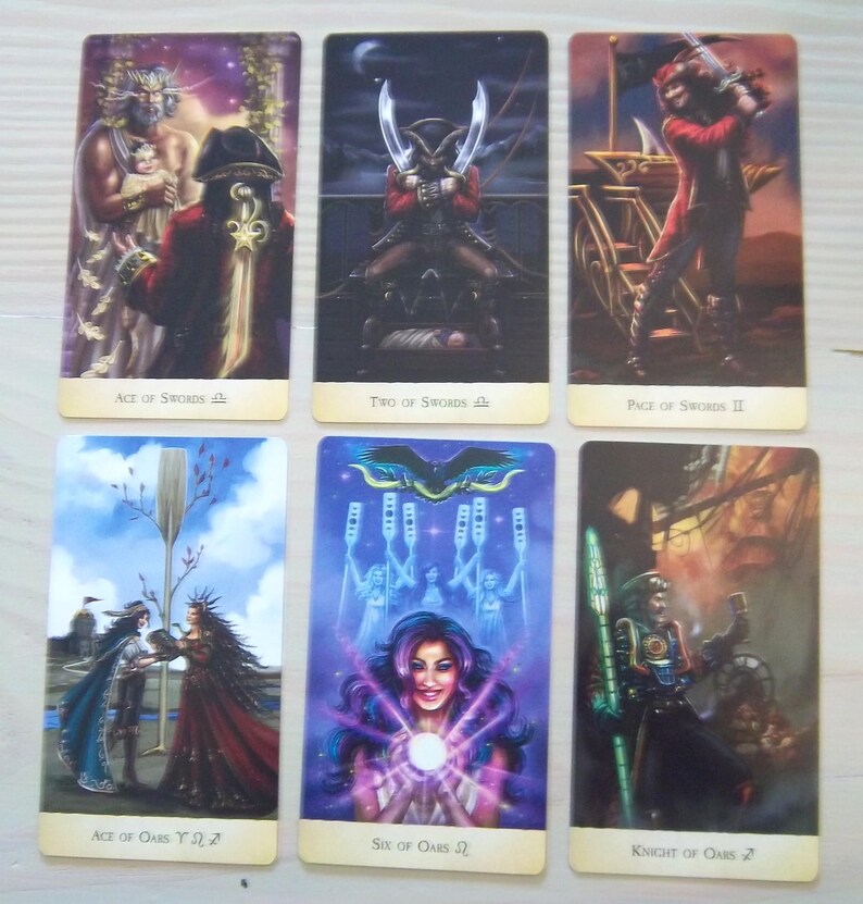 以下が含まれることがあります： 2列に並べられた6枚の長方形のタロットカード。上段：Ace of Swords、Two of Swords、Page of Swords II。下段：Ace of Oars、Six of Oars、Knight of Oars。各カードには、鮮やかな色彩で描かれた詳細なファンタジーイラストが施されています。