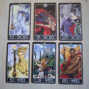 May include: Tarot card deck featuring ten cards with illustrations of people and symbols. The cards are black with silver trim and feature the suits of swords and wands. The cards include Ace of Swords, Ten of Swords, Queen of Swords, Ace of Wands, Four of Wands, and King of Wands.