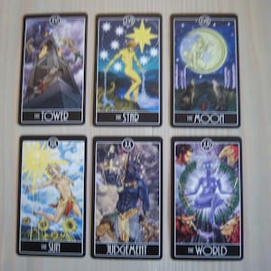 May include: A set of 10 tarot cards featuring illustrations of The Tower, The Star, The Moon, The Sun, Judgement, and The World. The cards are black with silver trim and feature colorful illustrations.