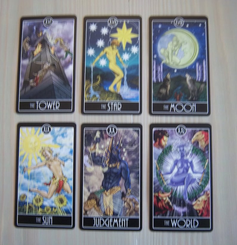May include: A set of 10 tarot cards featuring illustrations of The Tower, The Star, The Moon, The Sun, Judgement, and The World. The cards are black with silver trim and feature colorful illustrations.