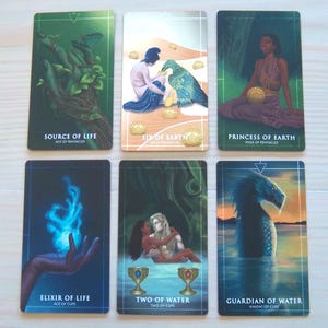 May include: Tarot card deck featuring illustrations of various elements, including a hand holding a green plant, a person feeding a bird, a woman sitting on a throne, a hand holding a blue flame, two people embracing, and a sea serpent. The cards are labelled with the names of the suits and the card number.