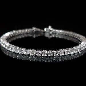 May include: A silver tennis bracelet with a row of clear cubic zirconia stones.
