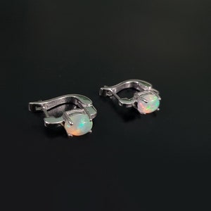 May include: A pair of silver hoop earrings with a white opal gemstone in each earring.