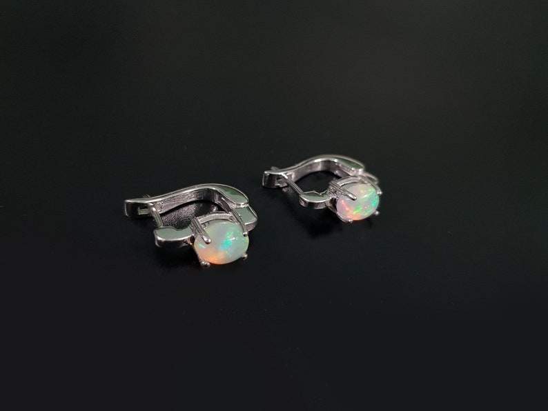 May include: A pair of silver hoop earrings with a white opal gemstone in each earring.
