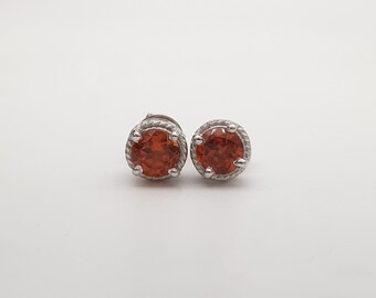 Op de afbeelding: Een paar zilveren oorbelletjes met oranje edelstenen, gezet in een zilveren zetting.