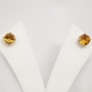 May include: A pair of gold stud earrings with round, faceted gemstones.