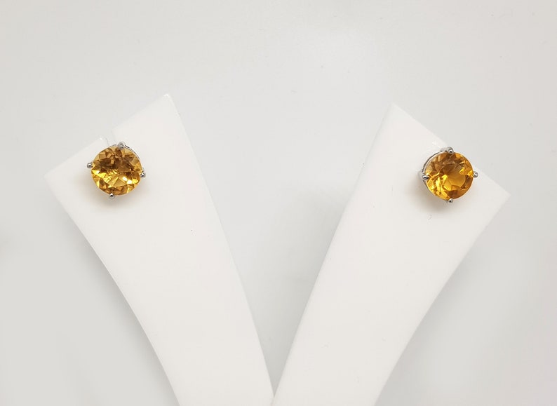 May include: A pair of gold stud earrings with round, faceted gemstones.