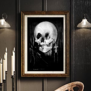 May include: A black and white print of a skull with a woman's reflection in the eye sockets. The woman is sitting at a vanity table with a mirror. The print is framed in a gold frame.