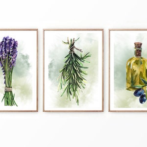 Puede incluir: Un conjunto de tres impresiones de acuarela que representan un ramo de lavanda, un ramo de romero y una botella de aceite de oliva con aceitunas. Las impresiones están enmarcadas en marcos de madera natural.