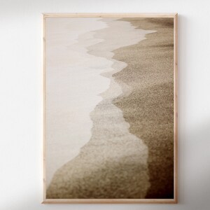 May include: A framed photograph of a beach scene with a close-up of the sand and waves. The image is in sepia tones, giving it a vintage feel.