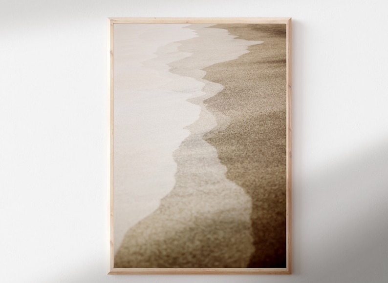 May include: A framed photograph of a beach scene with a close-up of the sand and waves. The image is in sepia tones, giving it a vintage feel.