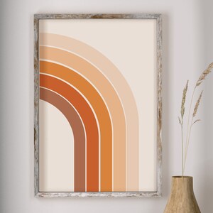 May include: A framed print with a geometric design of a half-circle made of orange, brown, and peach colored stripes on a cream background.