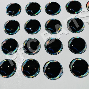 May include: A sheet of 16 black and iridescent fish eyes with a silver rim. The eyes are arranged in a 4x4 grid.