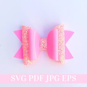 Pode incluir: Um laço de cabelo rosa com glitter e um acabamento brilhante e lustroso. O laço é feito de duas camadas de tecido, a camada superior é rosa sólida e a camada inferior é um tecido rosa com glitter.