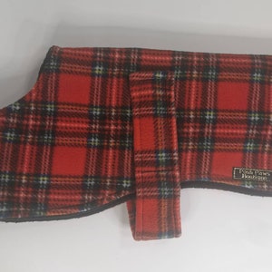 Peut inclure: Manteau pour chien en plaid rouge et noir avec une sangle noire et l'étiquette "Posh Paws Boutique".