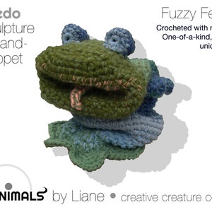 May include: A green, blue, and pink crocheted frog hand puppet. The puppet is a one-of-a-kind, sculptural design. The text "Fredo sculpture & hand-puppet" and "Fuzzy Feature Crocheted with mixed yarn One-of-a-kind, sculptural unique design" is visible in the image. The text "LIANIMALS by Liane • creative creature comforts" is also visible in the image.