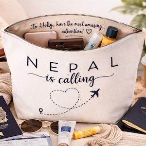 May include: A white canvas travel bag with the text "Nepal is calling" and a heart-shaped dotted line with an airplane. The bag is filled with travel essentials, including a passport, sunglasses, and toiletries.