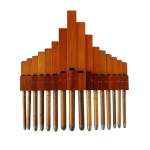 Może przedstawiać: Zabytkowy drewniany instrument muzyczny z szeregiem stopniowanych drewnianych piszczałek, ułożonych w kształt trójkąta. Piszczałki są w różnych odcieniach brązu, z metalowymi końcówkami. Prawdopodobnie rodzaj organów lub instrumentu dętego.