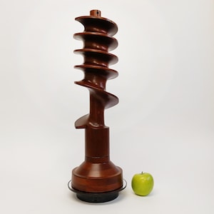 May include: A large, wooden sculpture in the shape of a spiral. The sculpture is made of dark brown wood and has a smooth, polished finish. It is about 30 inches tall and stands on a black base.