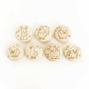 May include: Seven wooden round ornaments with different farm animal designs. The animals include a rabbit, a chicken, a sheep, a pig, a goose, a goat, and a cow. Each ornament has a white background with a brown outline and a brown fill for the animal.
