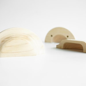 Peut inclure: Trois poignées de tiroir en bois de différentes formes. Deux sont en forme de demi-cercle et une est rectangulaire avec un dessus et un bas incurvés.