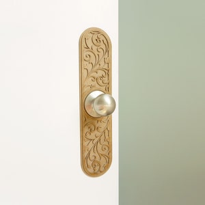 May include: A gold door knob with a decorative floral design on the backplate.