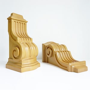 May include: Two wooden corbels with a decorative scroll design. The corbels are a light brown color and have a smooth finish.