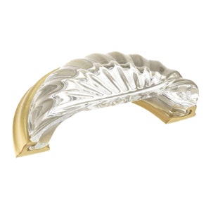 May include: A clear glass cabinet knob with a gold metal base. The glass has a textured, fan-shaped design.