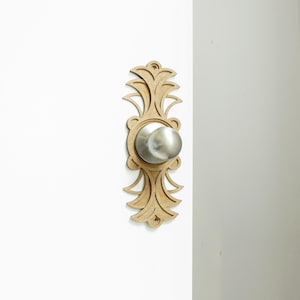 Peut inclure: Une poignée de porte en bois avec un design décoratif et orné. La poignée est argentée et le design est en bois brun clair.
