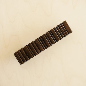 Puede incluir: Un tirador de puerta de madera marrón oscuro con un diseño acanalado.