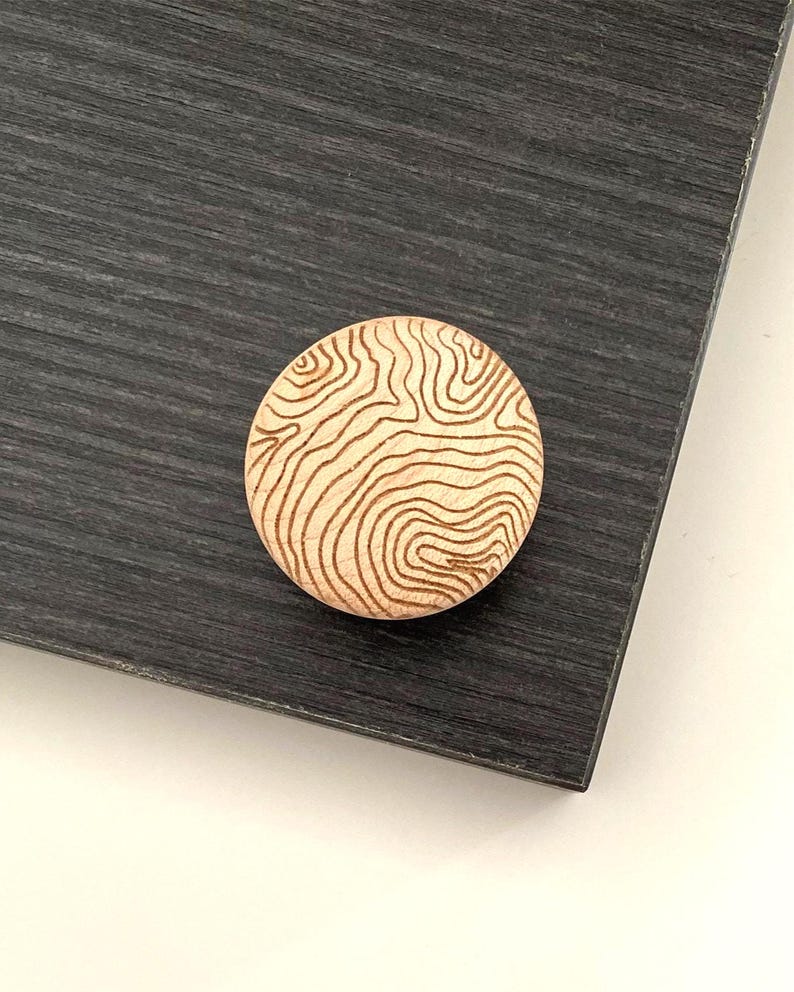 Peut inclure: Une tasse en c&eacute;ramique blanche avec une anse noire et le texte "But First, Coffee" en gras noir. La tasse est pos&eacute;e sur un fond flou, sugg&eacute;rant un cadre chaleureux.