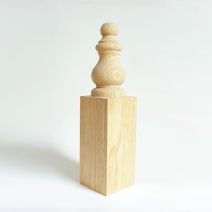 May include: A wooden finial with a rounded top and a bulbous base, sitting on a square wooden block.