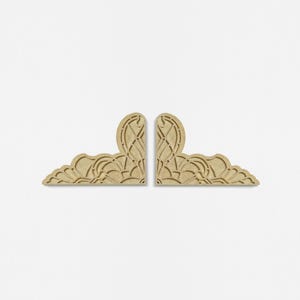 May include: Two wooden corner brackets with intricate cut-out designs. The brackets are light brown and have a symmetrical pattern.