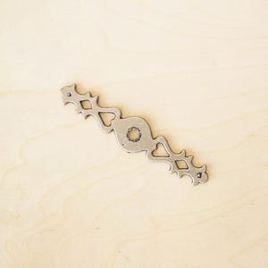 Könnte beinhalten: Ein silberner Metall-Schubladenzug mit einem dekorativen Design mit Herzen und Diamanten.