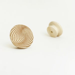May include: Two wooden knobs, one with a swirling pattern and the other plain. Both are light brown in colour.
