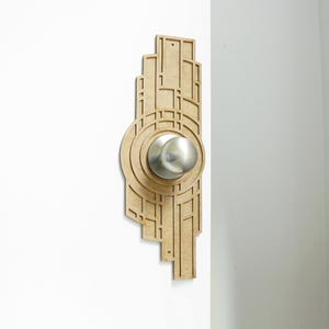 Könnte beinhalten: Ein hölzerner Türgriff im Art-Deco-Stil. Der Griff ist hellbraun und hat einen silbernen Knauf.