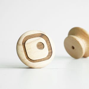 Op de afbeelding: Een witte keramische mok met een zwarte handgreep en de tekst "But First, Coffee" in een zwarte, vette letter. De mok staat op een houten oppervlak. De mok is ongeveer 10 cm hoog.