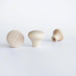 Pode incluir: Três botões de madeira em diferentes formas e tamanhos. Os botões são sem acabamento e têm uma cor de madeira natural.