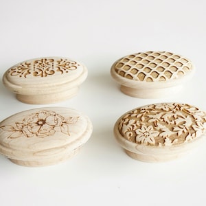 Pode incluir: Quatro puxadores de armário de madeira com designs decorativos. Os puxadores apresentam padrões intrincados, incluindo motivos florais, geométricos e ornamentais. A madeira de cor clara proporciona uma estética natural, adequada para vários estilos de decoração.