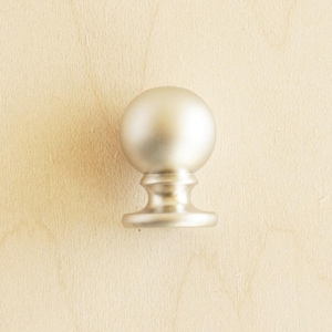 Może przedstawiać: Srebrny, okrągły gałka do szafki z gładkim, błyszczącym wykończeniem.