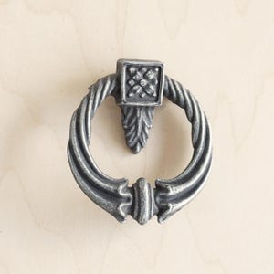 Peut inclure: Poignée de porte en métal argenté avec un motif floral décoratif. La poignée est en forme de corde torsadée.