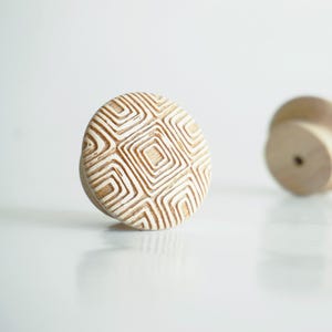 Op de afbeelding: Een witte keramische mok met een zwart handvat en de tekst "But First, Coffee" in een vetgedrukte, zwarte letter. De mok staat tegen een wazige achtergrond, wat een gezellige setting suggereert.