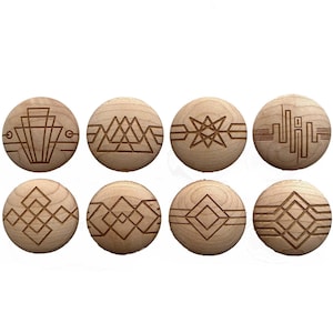 May include: Eight wooden cabinet knobs with various geometric designs etched into the surface. The knobs are round and made of light-colored wood. The designs include lines, triangles, and starburst patterns.