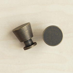 May include: Two antique brass cabinet knobs, one round and one cone-shaped.