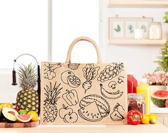 May include: A brown jute tote bag with black line drawings of various fruits and vegetables, including pineapples, apples, oranges, grapes, bananas, and watermelons. The bag is sitting on a wooden table with a variety of fruits and vegetables in front of it.