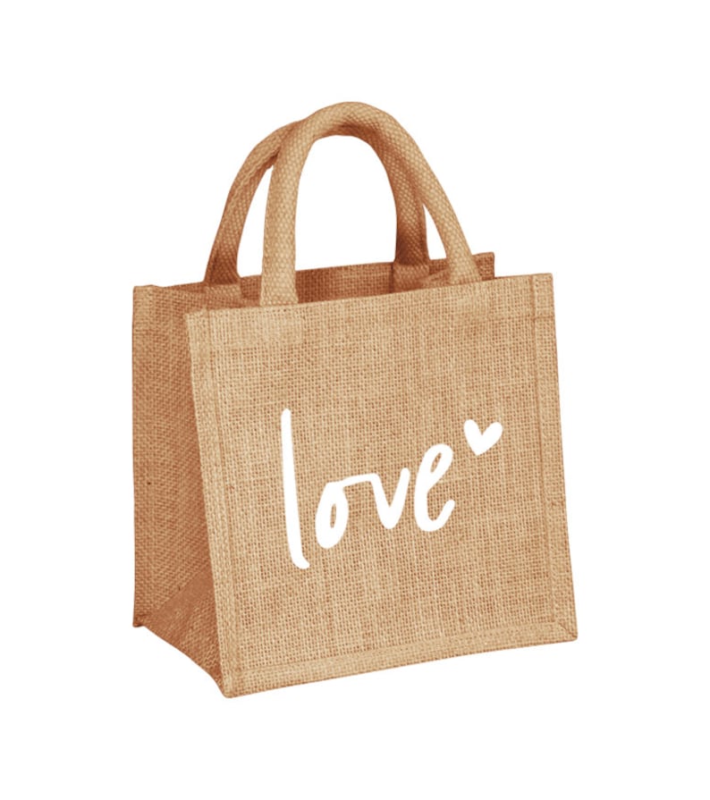 Pu&ograve; includere: Una piccola borsa di juta marrone con la scritta "love" in bianco e un piccolo simbolo di cuore.