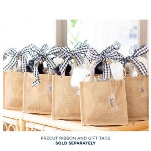May include: A group of eight brown burlap gift bags with black and white checked ribbon and gift tags. The tags have names written on them, including "Katie" and "Suzy".
